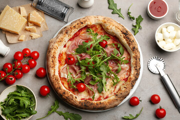 Tasty pizza with meat and arugula on grey table, flat lay