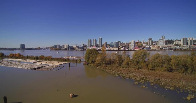 Modern City Of New Westminster, British Columbia, Canada Aerial over Fraser River logging Quayside boardwalk on a bright day with blue sky