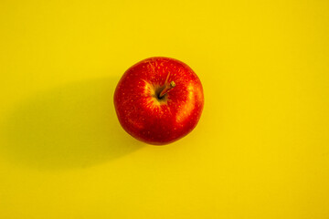 red apple on a bright yellow background with trendy sunlight