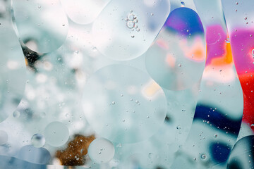 Close-up of the movement of oil droplets on the water surface. Colorful abstract macro background...