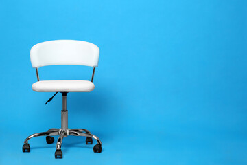 Comfortable office chair on light blue background, space for text
