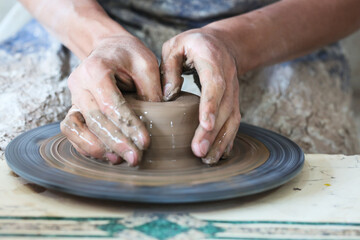 Potter hands making in clay on pottery wheel. Potter makes on the pottery wheel