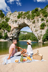 couple men and woman picnic on the beach of the The famous natural bridge of Pont d'Arc in Ardeche...