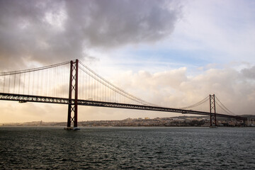 Fototapeta na wymiar The 25 April bridge (Ponte 25 de Abril) - famous bridge in Lisbon and among of the longest ones in Europe. 