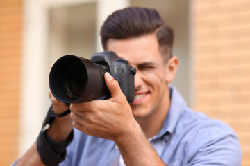 Photographer taking picture with professional camera outdoors, focus on device