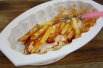 Übrig gebliebene Pommes mit Ketchup, in einer weißen Schale
