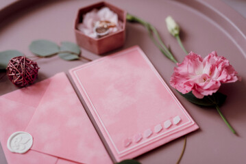 wedding invitation in a gray envelope on a table with green sprigs