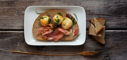 snack appetizer with wholemeal bread, raw ham and smoked provola