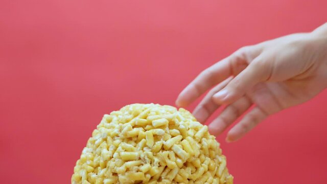 Woman takes pieces of chack-chack from large ball on pink