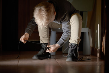 Preschooler child learning to tying shoelace at home, selective focus