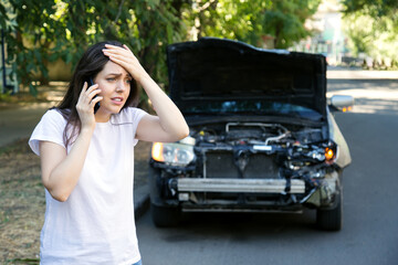 Driver woman in front of wrecked car in car accident. Scared woman in stress holding her head after...