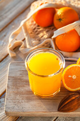 Glass of freshly sqeezed orange juice on a wooden table. Natural source of vitamins, healthy beverage for ideal breakfast. Bright sunny summer day. Close up, copy space for text.