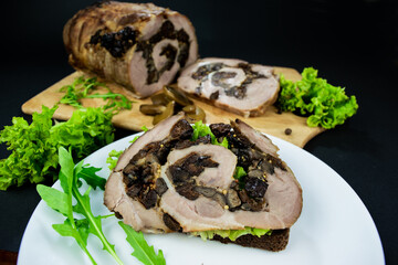 Sandwich with meat and herbs, salad leaves and arugula for a snack on a white plate on black background.