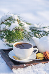 White cup of hot tea and teapot on a bed of snow and white background, close up