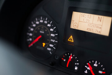 Capital T and steering wheel warning lit on vehicle display of a heavy truck. Digital tachograph indicates 15 minutes left before the driver must take a brake after 4,5 hours of driving.