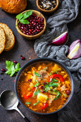 Homemade Meat Tomato soup with beef and bean stew, vegetables on a stone tabletop.