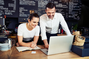 Small business bookkeeping. Two cafe owners calculating expenses with laptop