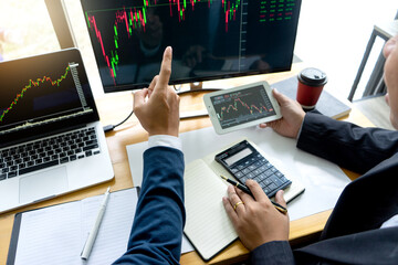 Businessmen are pointing to monitor to view stock market data on desktop