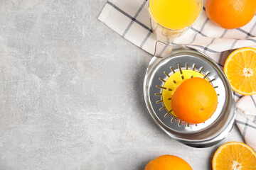 Fresh ripe oranges, juice and squeezer on grey table, flat lay. Space for text