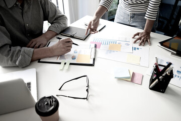 Diverse male mentor and intern talking pointing on paper at work desk