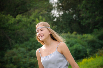 Fototapeta na wymiar beautiful blonde laughs in a gray dress on a walk in the park