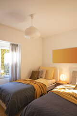 Modern bedroom with two singles beds with clean bed sheets and large pillow above. White wall