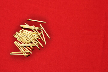 Background. Scattered wooden matches on a red cotton background.