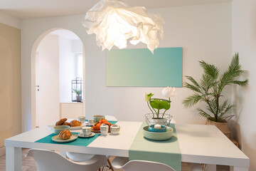 Elegant and romantic white table ready for breakfast with brioche, cups for coffee and fruits