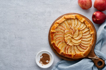 Apple pie, galette with fruits, sweet pastries on gray backdrop, sweet crostata on cutting wooden...