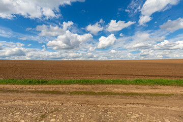 a plowed field against the sky with clouds. Spring sunny day