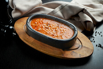 Oriental cuisine dish - lamb with beans in red sauce in a black plate on a dark background