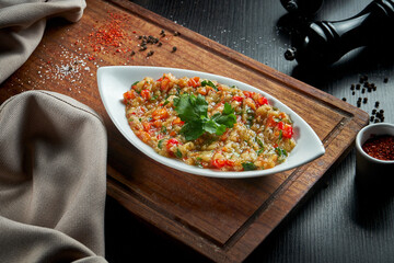 Traditional Arabian eggplant dish Baba Ghanoush with olive oil and herbs. Wood table. Close up