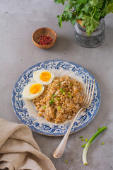 Coarse oat porridge with eggs and onions. Hearty healthy breakfast or lunch concept. Selective focus.