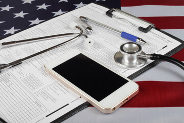 mobile phone and medical phonendoscope on american flag, close-up, selective focus