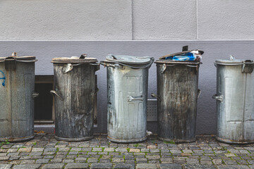 Metal trash cans lined up together in back alleyway in Cesky Krumlov, Czech Republic.