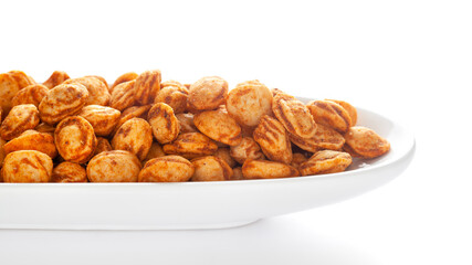 Roasted Crunchy Peanuts in a white ceramic oval bowl, made with peanuts. Pile of Indian spicy snacks (Namkeen), under backlight, side view, against the white background.
