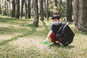A boy pick up plastic bottle trash and puts on the trash bag in the forest, save the planet and...