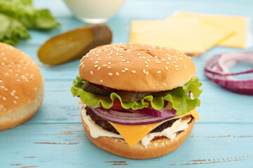 Homemade burger ingredients arranged on blue wooden background.