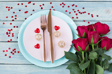 two plates, cutlery, a bouquet of roses and hearts