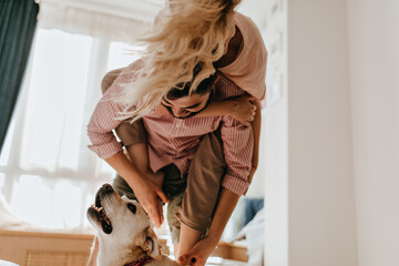Stylish guy and girlfriend have great time with their white dog. Man in striped shirt holds his...