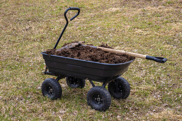 humus in a four-wheeled garden cart. Cloudy spring day