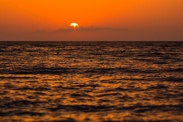 Amazing sea sunset on the pebble beach, the sun, waves, clouds