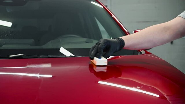 Close-up applying ceramic coating on the red car.