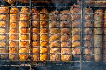 sausages are baked on coals in a metal grill. Sunny evening