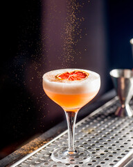 yellow tropical cocktail on bar counter sprinkled with cinnamon powder