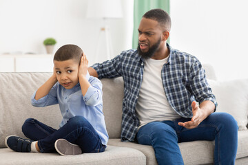 Irritated Black Father Shouting At Unhappy Little Son At Home.