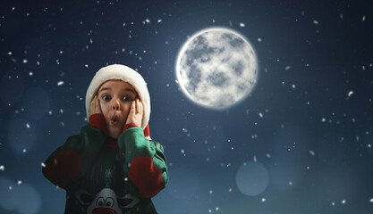 Fototapeta na wymiar Surprised little girl in Santa hat on full moon night. Christmas holiday