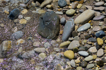 pebble stones on the sea beach, the rolling waves of the sea with foam