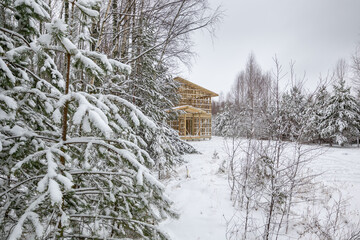 Fototapeta na wymiar a frame house under construction in the forest. Dense forest, winter