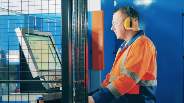 Computerized machine is getting operated by a factory worker